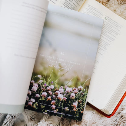 Gospel Hope in Grief and Loss journal page featuring serene field of flowers with scripture verse 'The Lord of Armies is with us, the God of Jacob is our stronghold' offering comfort and hope