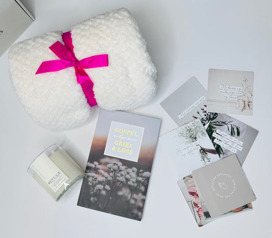 Detailed view of Grief and Comfort Care Box contents including scripture verse cards for grief, Gospel Hope in Grief and Loss journal, Refuge sea salt and ozone soy candle with 2 Samuel 22:31 verse, and soft cozy blanket displayed outside box