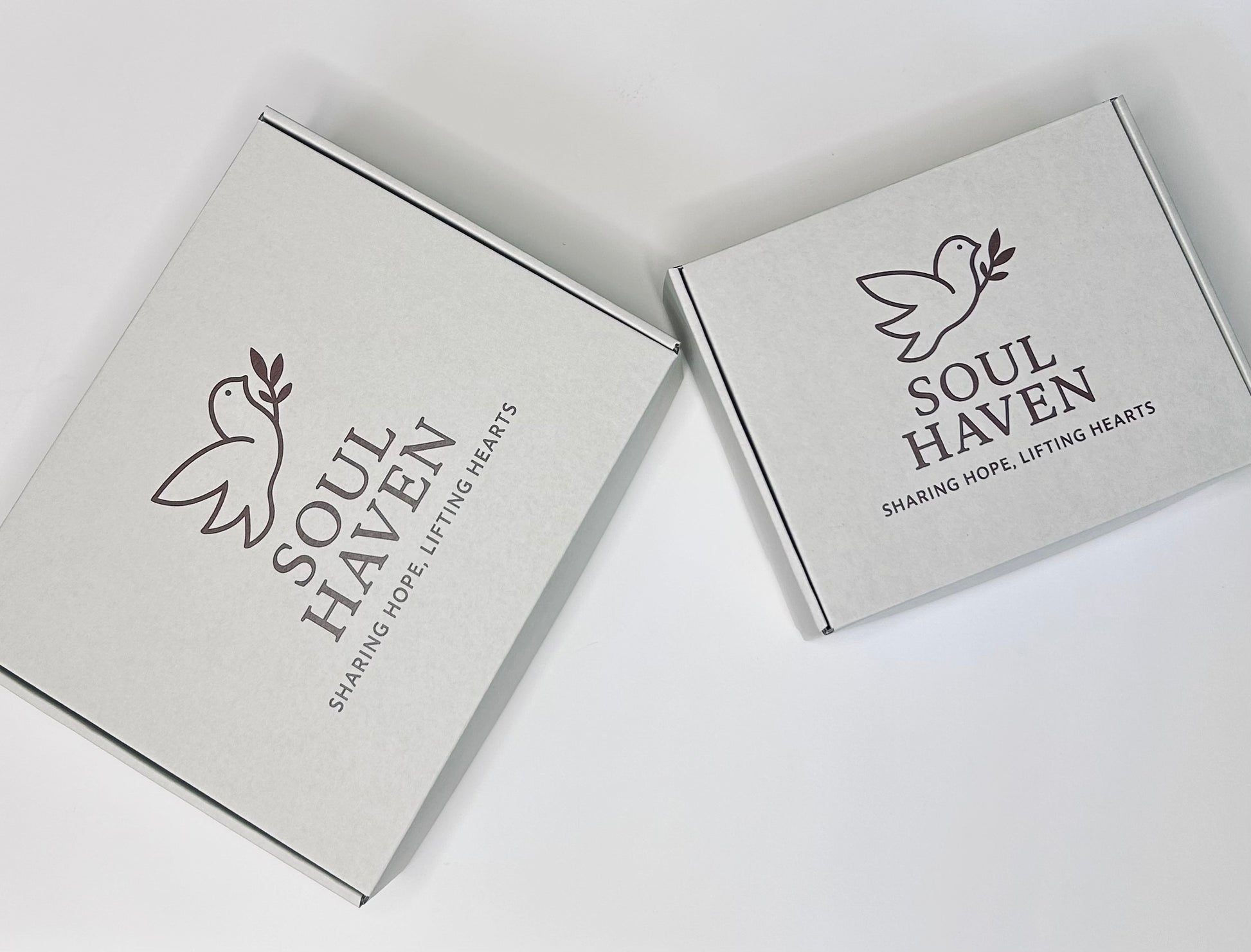 Bird's eye view of Soul Haven gift boxes in two sizes showing elegant packaging for Grief and Comfort Care Box, thoughtfully designed for meaningful gift presentation