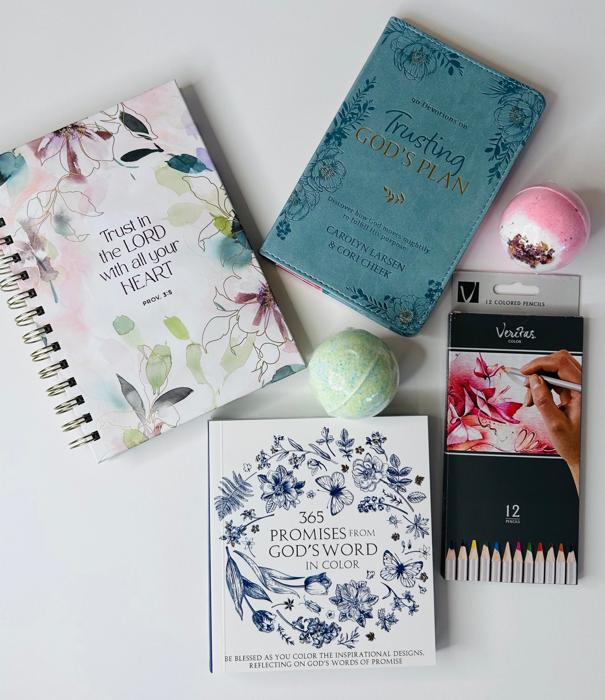 Trust in the Lord care box contents laid out showing 365 Promises from God's Word coloring book, Trust in the Lord journal, Trusting in God's Plan devotional, 12-piece Veritas colored pencils and two bath bombs for anxiety relief and peace