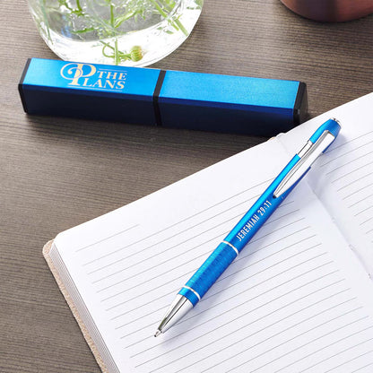 The Plans blue stylish pen with Jeremiah 29:11 laid on top of a blank lined notebook on a desk with the blue gift case above the notebook included in Teen Boy Blessing Box